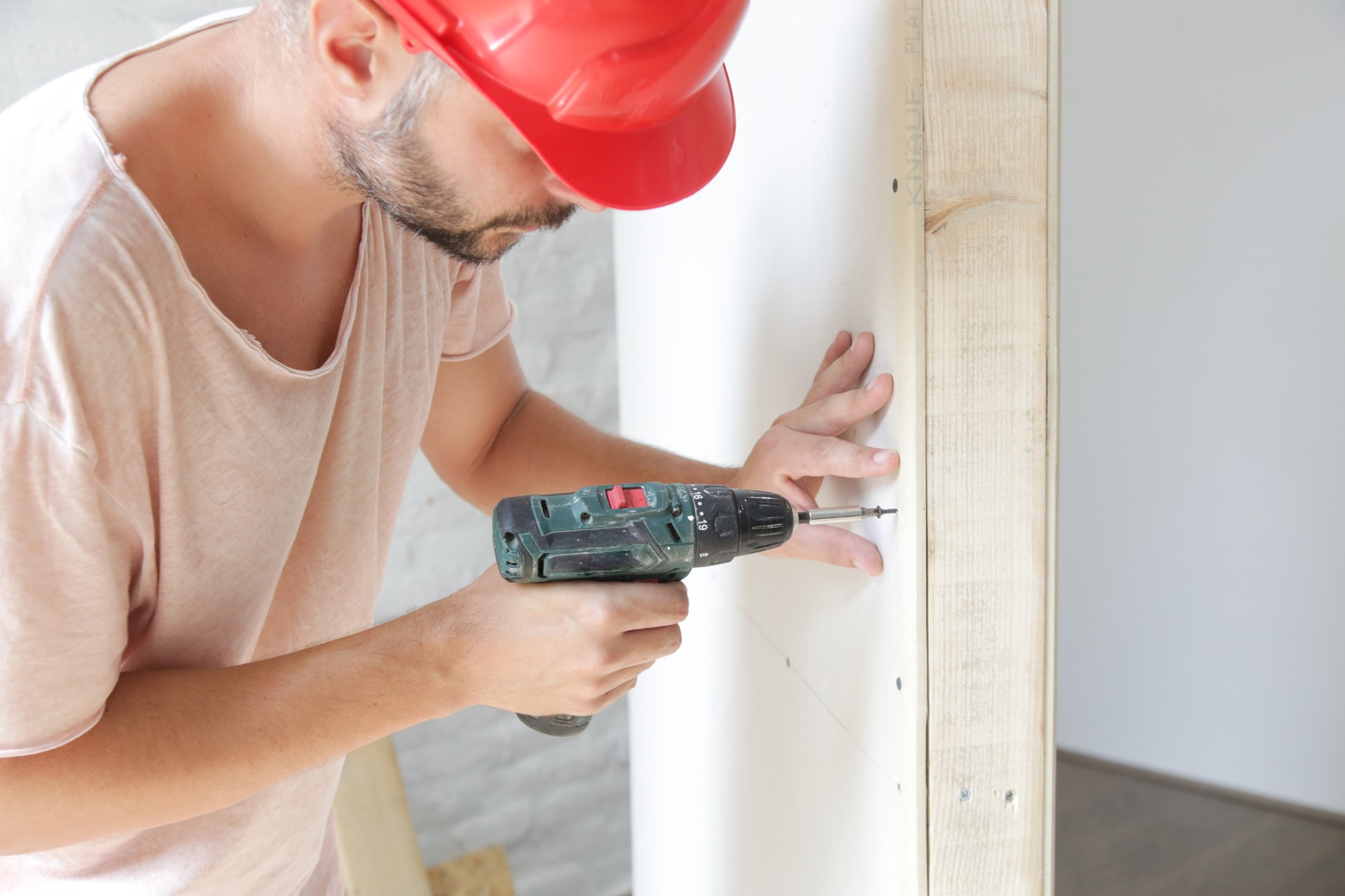 Handyman drilling screws into plasterboard with an electric screwdriver, home improvement concept